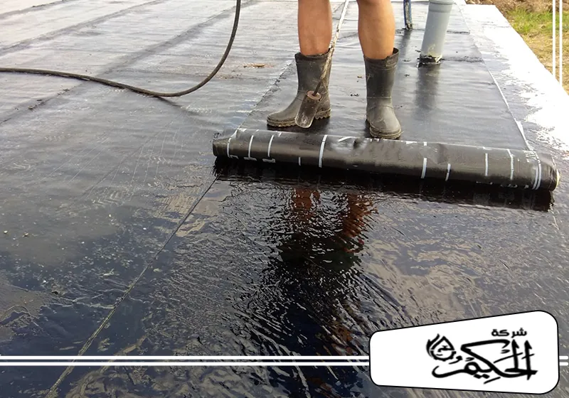 شركة العزل الحراري للأسطح في ام القيوين 0547842313 شركة الحكيم عامل يطبق مادة عوازل اسطح في ام القيوين باستخدام أداة التدحرج على سطح السقف.