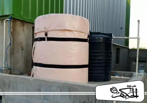 عزل خزانات ارضيه بابوظبي خزان رأسي صغير معزول باستخدام غطاء عزل جاهز قابلة للفك والتركيب باللون البيج الفاتح. يتم تثبيت الغطاء عبر أحزمة سوداء عريضة