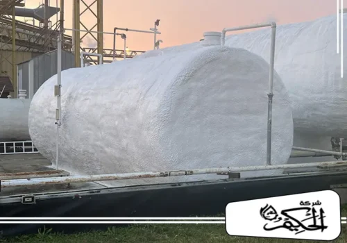 عزل اسطح وخزانات في ابوظبي تُظهر الصورة خزانين أفقيين ضخمين في موقع صناعي، مغطيين بطبقة سميكة وناصعة من العزل الحراري الرغوي الأبيض.