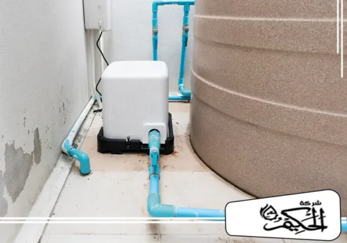 عزل خزانات الماء بالفجيرة مشهد خارجي يوضح خزان مياه كبير مُركَّب بجوار جدار وتظهر عليه علامات الرطوبة وتلف الطلاء